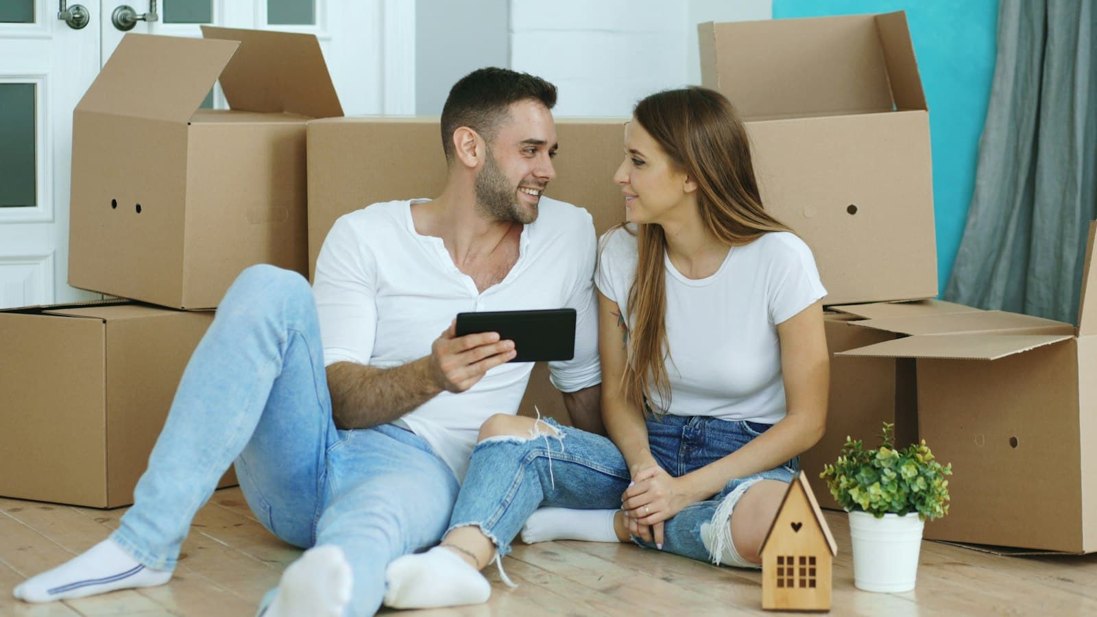 Casal procurando imóvel pelo tablet entre caixas de mudança